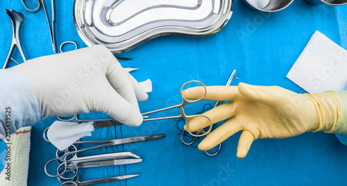 Surgeon working in operating room, hands with gloves holding sci photo