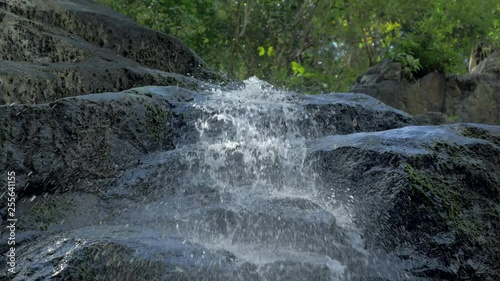 Close-up slow motion shot of small waterfall in the tropical rainforest jungle of Philippines. Small hidden rocky waterfall in jungle valley. Waterfall from a small mountain river in low mountains. photo