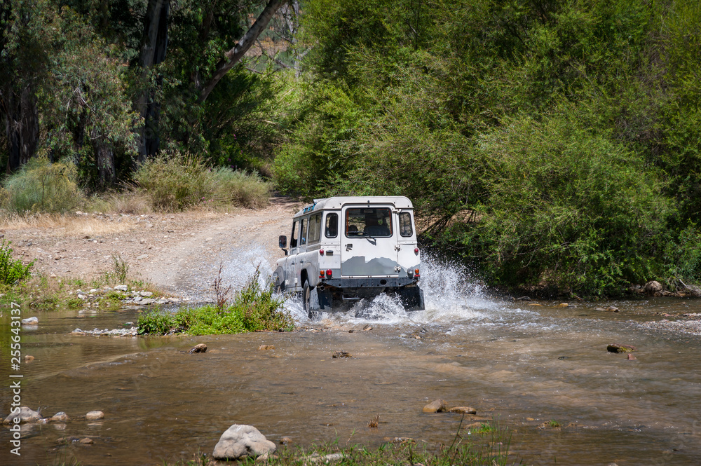 Rural Andalucia, Andalusia. Spain. 4WD vehicle crossing river. Back view.