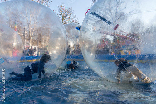 Unidentified children play having fun inside large tarsparent balls on the water photo