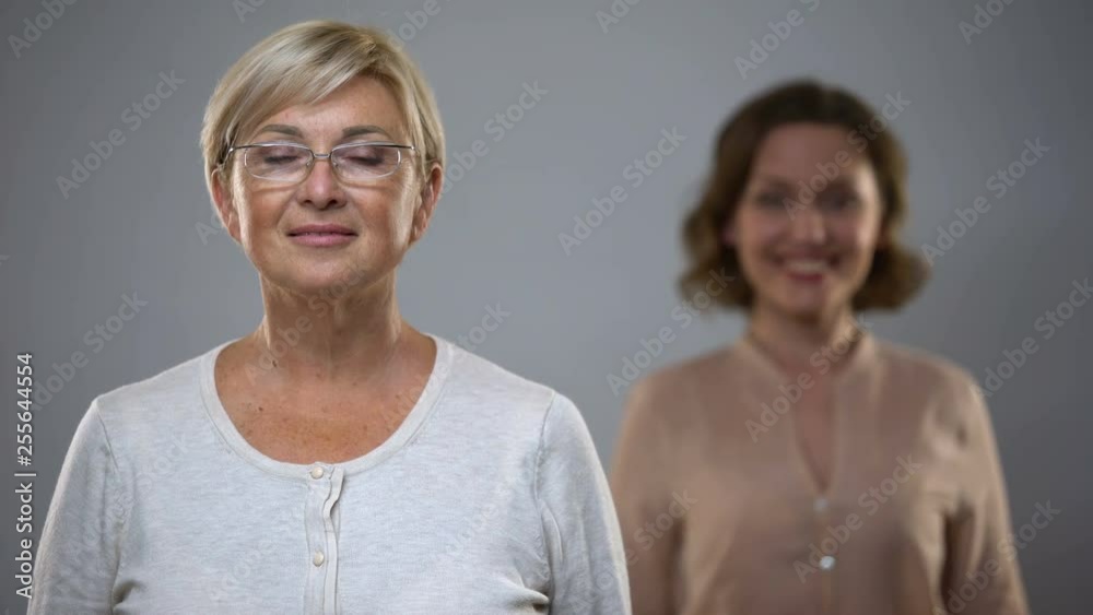 Beautiful mature lady looking in camera, young woman smiling behind, happy past Beautiful mature lady looking in camera, young woman smiling behind, happy past