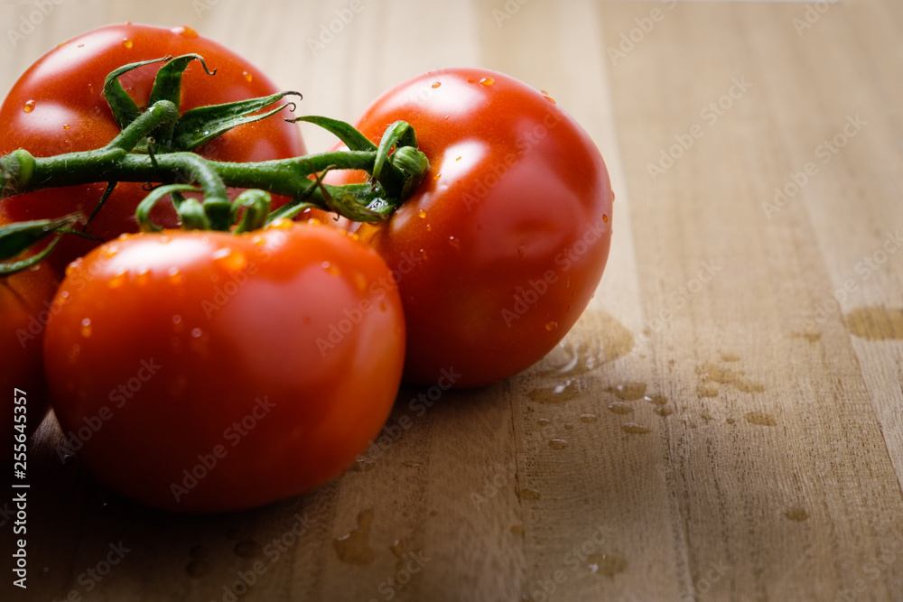 Tomatoes panicles with water drops on a wooden chopping board Tomatoes panicles with water drops on a wooden chopping board