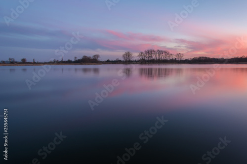 Calm lake and pink clouds after sunset