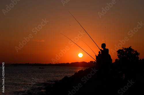 Fisherman on a shore at sunset