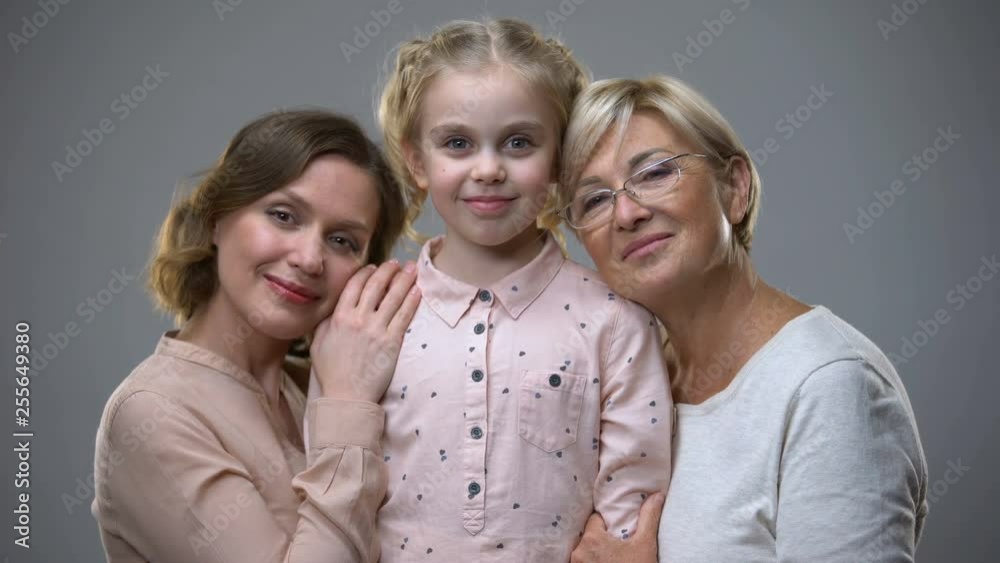 Adult women hugging little girl on grey background, love for child, family care Adult women hugging little girl on grey background, love for child, family care