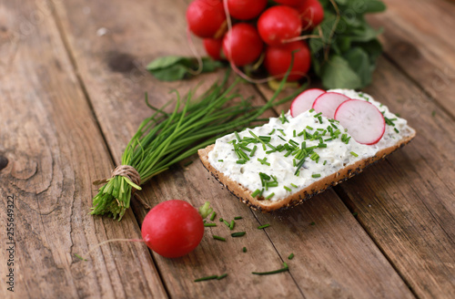 healthy breakfast - wholemeal roll with quark and fresh chive, radish on a rustic wooden table 
