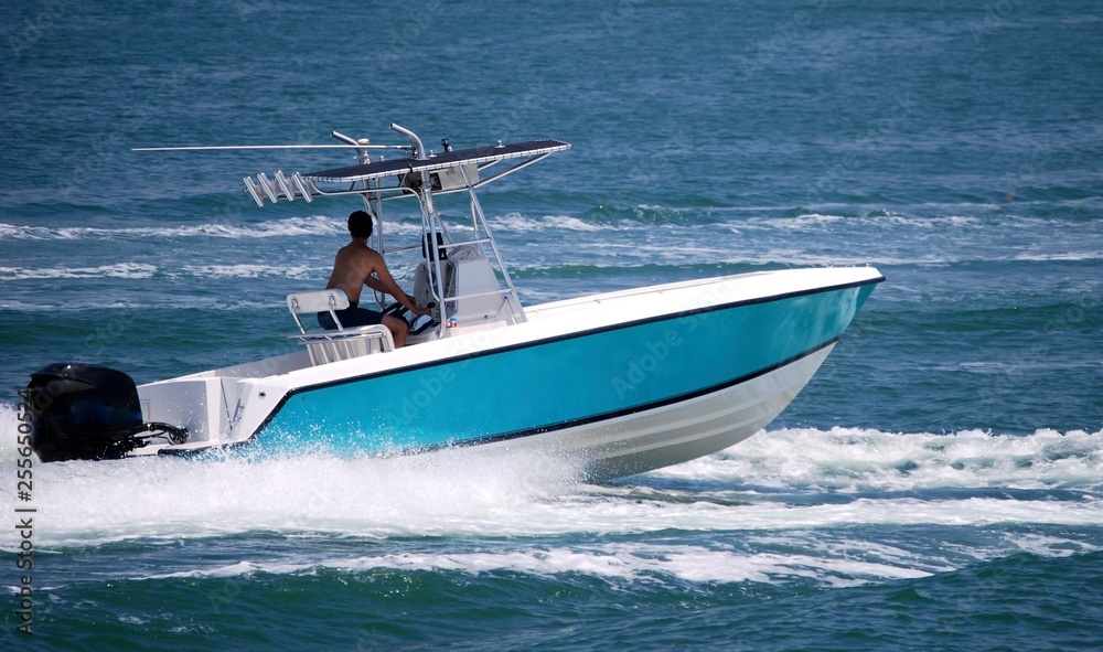 Fototapeta premium Open sport fishing boat light blue with white trim speeding on the Florida Intra-Coastal Waterway off Miami Beach.