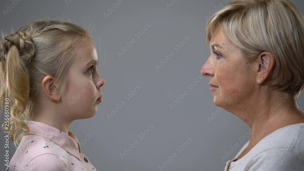 Senior lady looking at little girl, present past reflection, childhood memories Senior lady looking at little girl, present past reflection, childhood memories