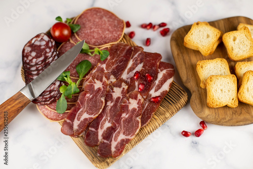 Meat, sausage, toasts and seeds of pomegranate on a marble background