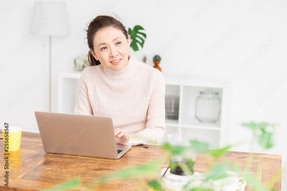 部屋でラップトップコンピューターを見るシニア女性 部屋でラップトップコンピューターを見るシニア女性