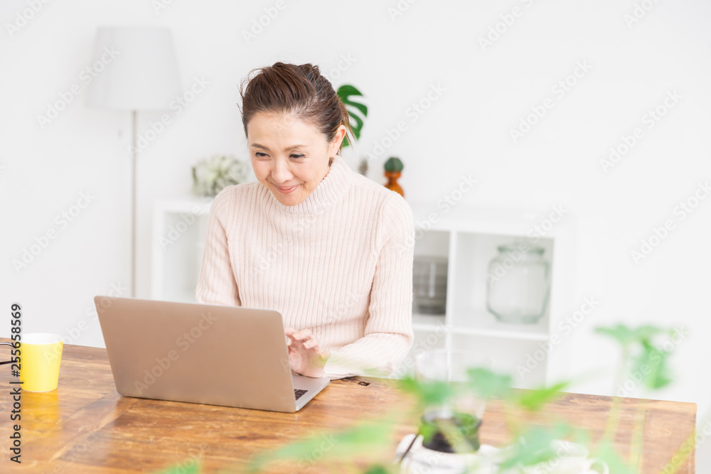 部屋でラップトップコンピューターを見るシニア女性 部屋でラップトップコンピューターを見るシニア女性
