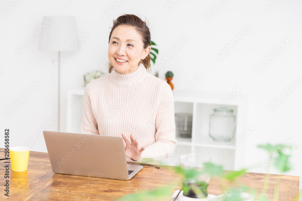 部屋でラップトップコンピューターを見るシニア女性 部屋でラップトップコンピューターを見るシニア女性