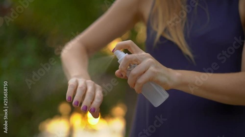 Superslowmotion shot of a beautiful young woman applying an antimosquito repellent spray on her skin. A tropical background. Mosquito defense concept photo