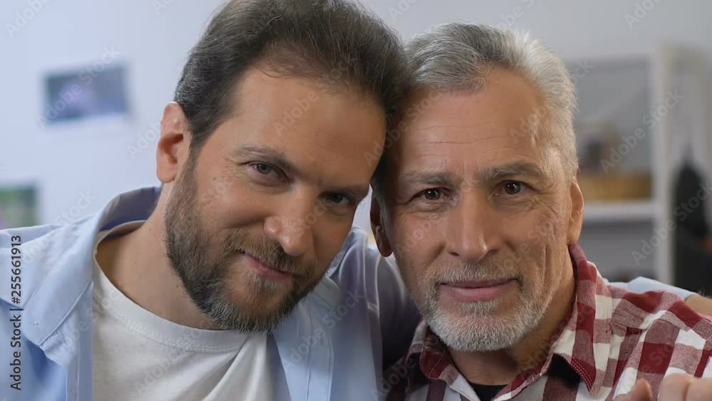 Handsome son and father looking into camera, friendly relationships, close-up Handsome son and father looking into camera, friendly relationships, close-up
