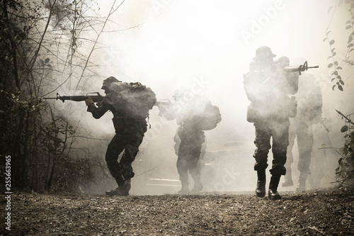Army patrols in the forest, coming out of the smoke and fog.