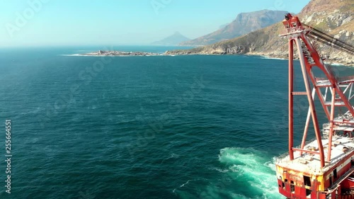 Beautiful shipwreck in Cape Town on the coast with ocean rocks and mountains, panning right and up, slowed down slightly. Focus on mast and mountains. photo