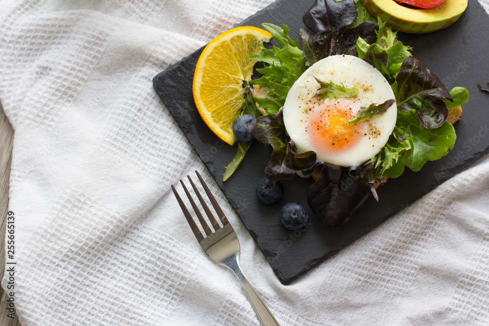 Fried eggs with bread toast on lettuce in a black plate.