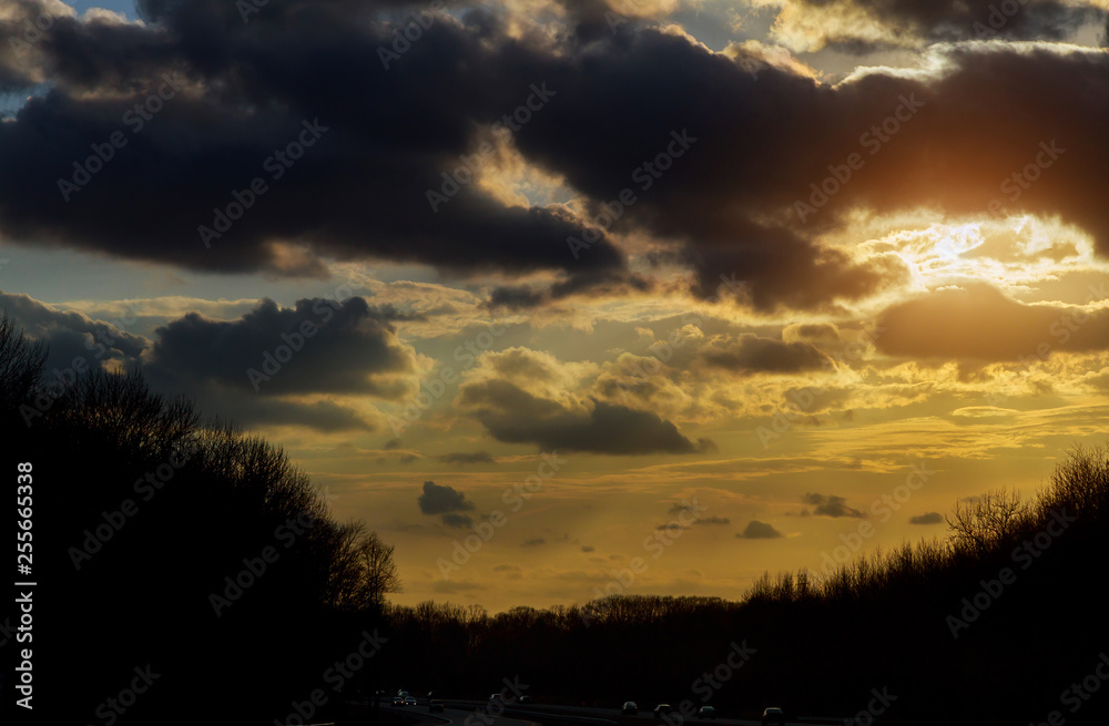 sunset in clouds with sunrays over road to horizont