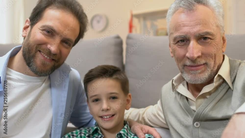 Father and grandpa hugging boy and looking into camera, family time at home Father and grandpa hugging boy and looking into camera, family time at home