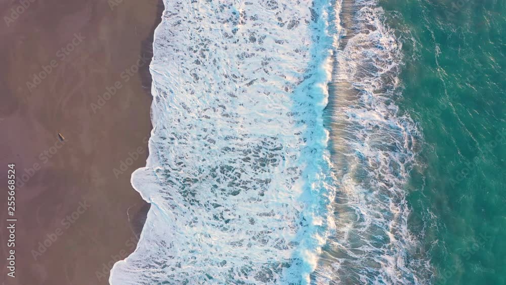 Drone slowly descending over turquoise ocean and beach and waves coming ashore Drone slowly descending over turquoise ocean and beach and waves coming ashore
