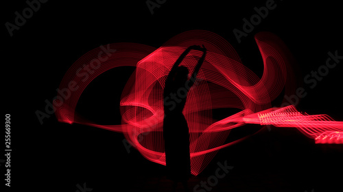 Woman silhouette against red backlight. Light painting photography. Long exposure.