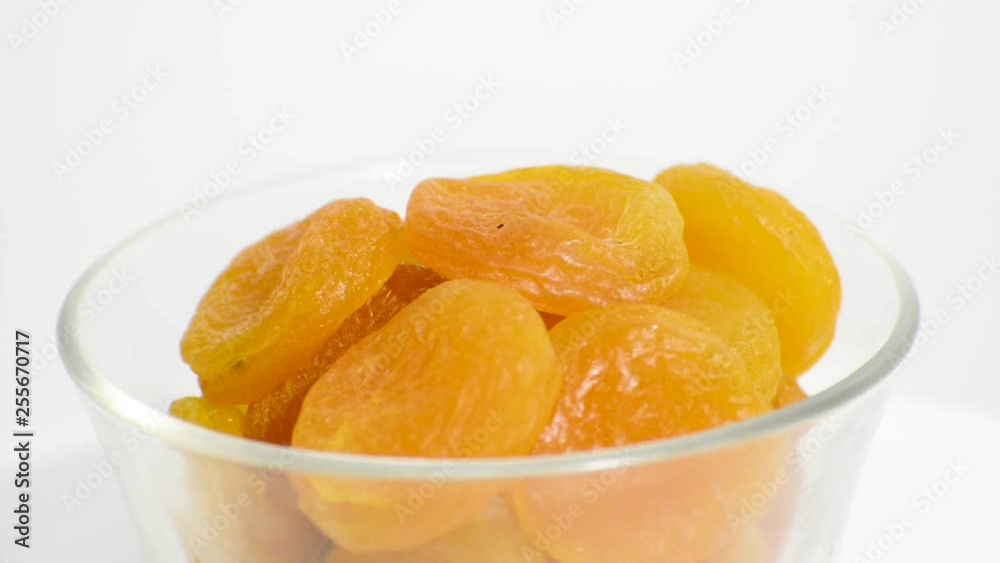 Transparent bowl with Turkish apricot rotating on a white background. Flat plane. High angle shot Transparent bowl with Turkish apricot rotating on a white background. Flat plane. High angle shot
