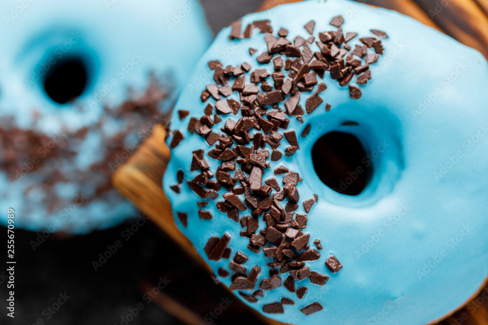 Concept of cooking, baking and food - close-up. Donuts in blue glaze with chocolate sprinkles on a decorative board. Trend colors.