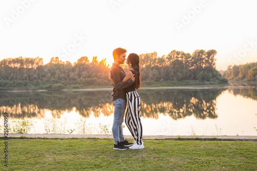 Love, romantic and nature concept - young couple hugging near the lake