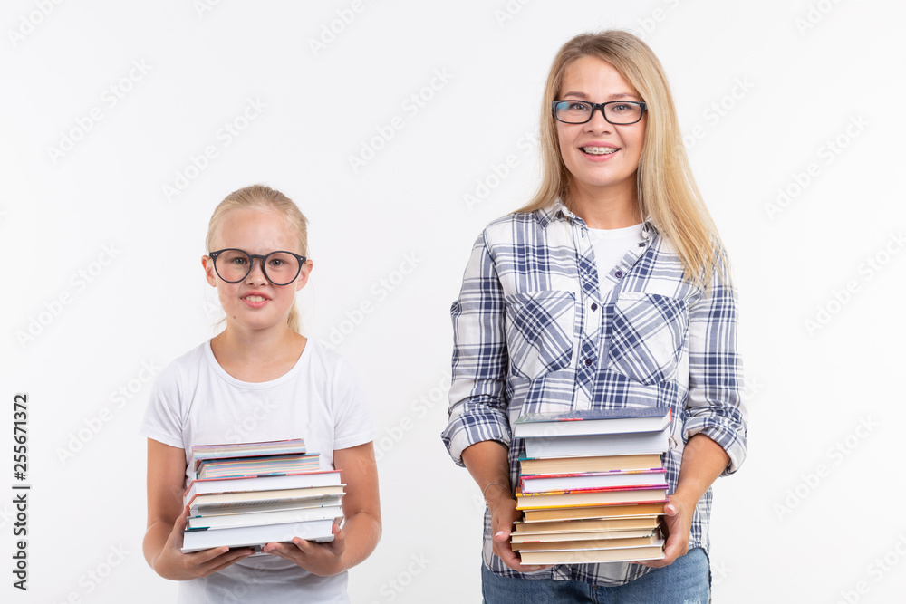 Knowledge, reading and education concept - Mother and daughter holding a books on white background.