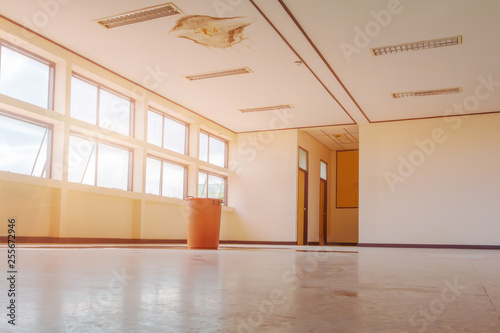 water leak drop interior office building in red bucket from Ceiling and flow on terrazzo floor