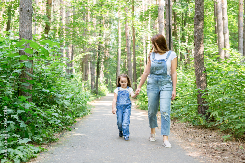 Fototapeta premium Family, children and nature concept - Portrait of attractive woman and little child girl walking together