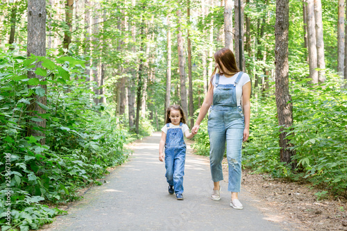 Family, children and nature concept - Portrait of attractive woman and little child girl walking together © satura_