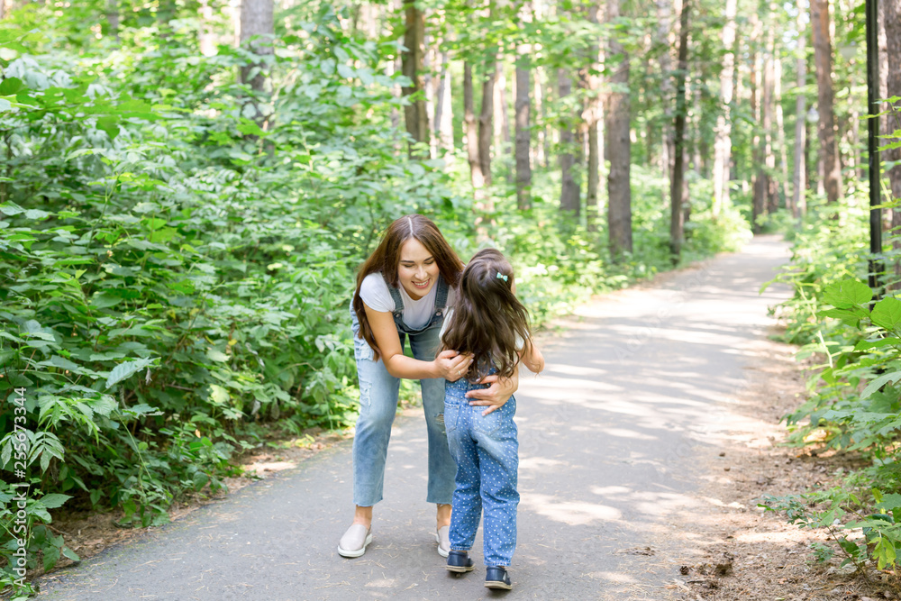 Family and nature concept - Young woman hug little girl in the park