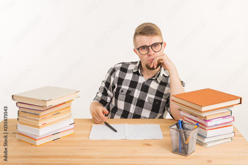 Education, knowledge and people concept - student in glasses thinking about exams and learning the literature Education, knowledge and people concept - student in glasses thinking about exams and learning the literature