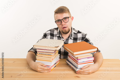 People, exam and education concept - Exhausted and tired student dressed in plaid shirt sitting at the wooden table with many books