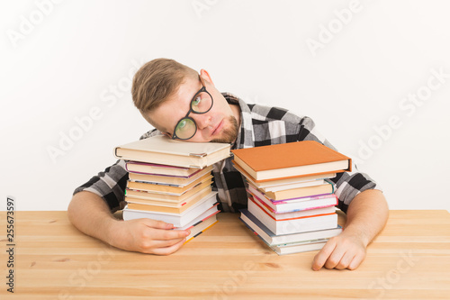 People, exam and education concept - Exhausted and tired student dressed in plaid shirt sitting at the wooden table with many books