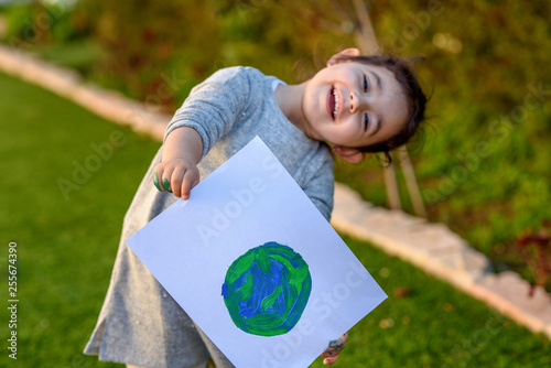 Portrait of the cute little girl holding the drawing earth globe. Child drawng a picture of earth.Earth day, plastic free and zero waste concept. photo