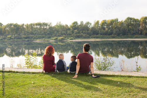 Childhood and nature concept - Family with little sons sitting on the green grass © satura_