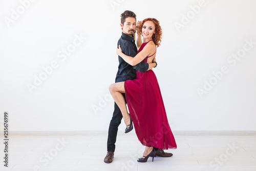 Social dance, bachata, kizomba, salsa, tango concept - Woman dressed in red dress and man in a black costume over white background with copy space