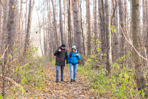 adventure, travel, tourism, hike and people concept - smiling couple walking with backpacks over autumn natural background