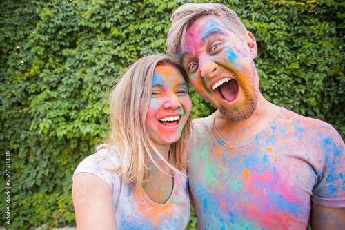 Festival of holi and technology concept - young couple making selfie at the festival