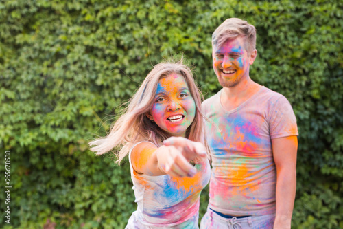 Holiday, holi and people concept - Happy couple having fun with multicolored powder on their faces