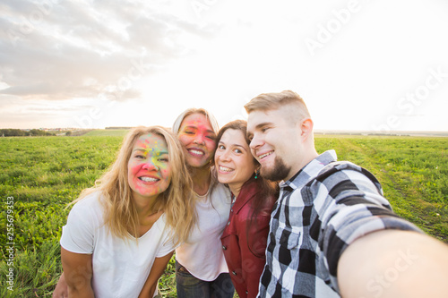 Festival and technology concept -group of friends taking selfie or self picture using cell phone or smartphone on Holi festival.