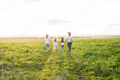 Family, summer and holiday concept - Group of women and girls going away in green field © satura_