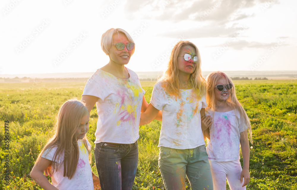 Festival of holi, friendship, happiness and holidays concept - little girls and women in glasses hugging on the festival of Holi. Festival of holi, friendship, happiness and holidays concept - little girls and women in glasses hugging on the festival of Holi.