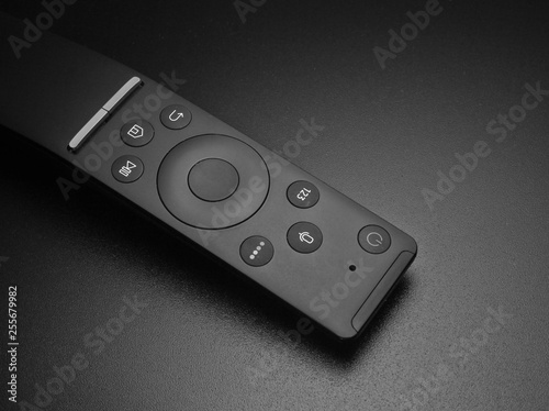 Tv remote closeup on a durk black background.