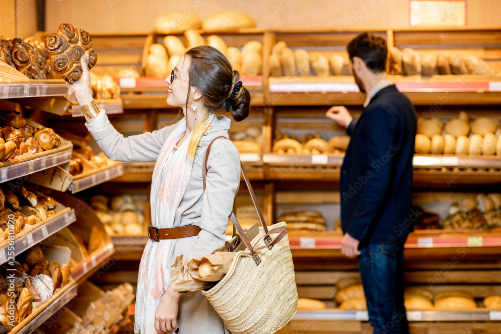 Man and woman choosing fresh pastries in the bakery department of the supermarket