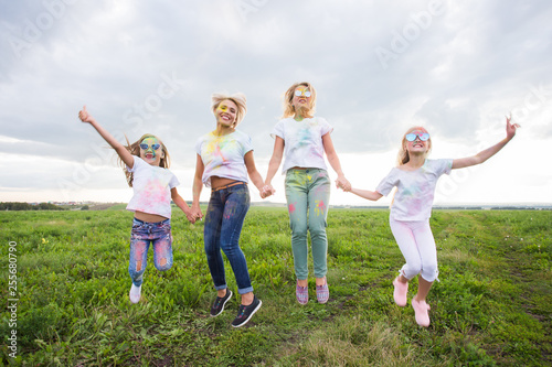 Festival of Holi, friendship and holidays concept - young female people on the color dancing and having fun