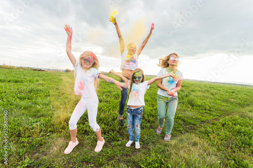 Festival of Holi, friendship and holidays concept - young female people on the color dancing and having fun