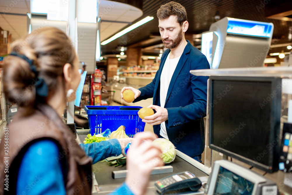 Handsome businessman putting products on the cash register buying food in the supermarket Handsome businessman putting products on the cash register buying food in the supermarket